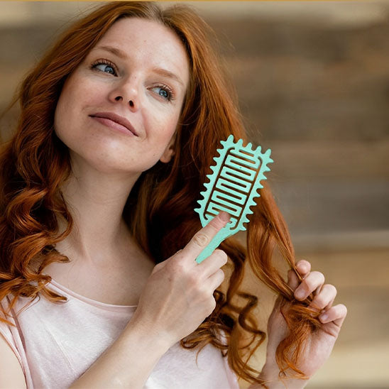 femme brossant ses cheveux avec brosse cheveux boucles vert
